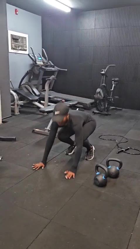A client in a bear crawl beside a kettlebell