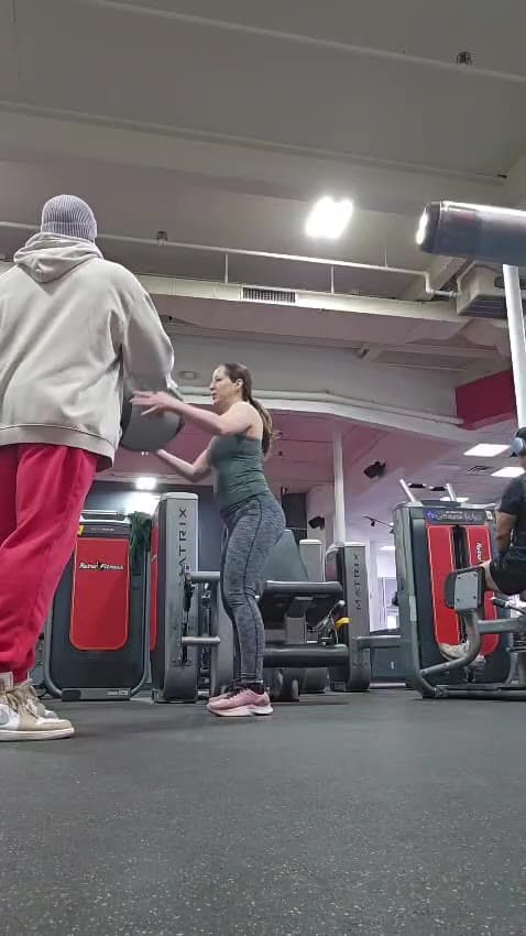 A client walking a loaded carry across the gym floor