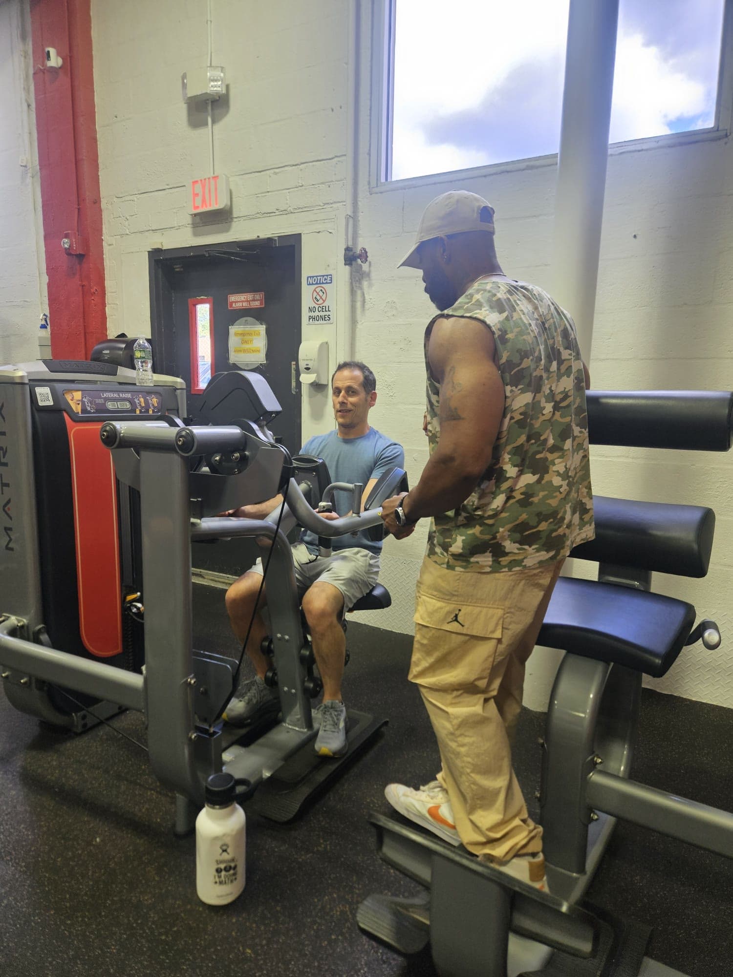 Daine Chang beside a client on a seated machine, setting the movement