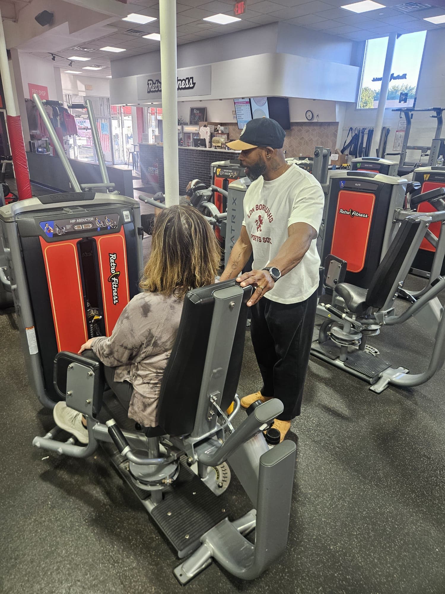 Daine Chang standing over a client seated on a machine