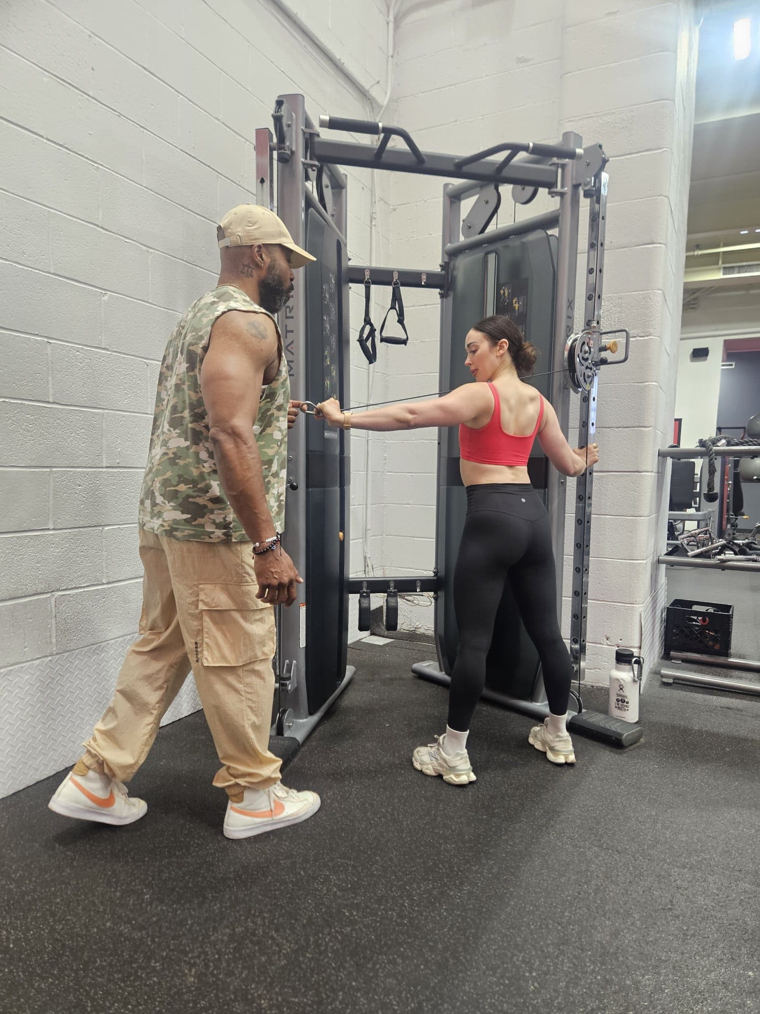 Daine Chang correcting a client's arm position at the cable tower