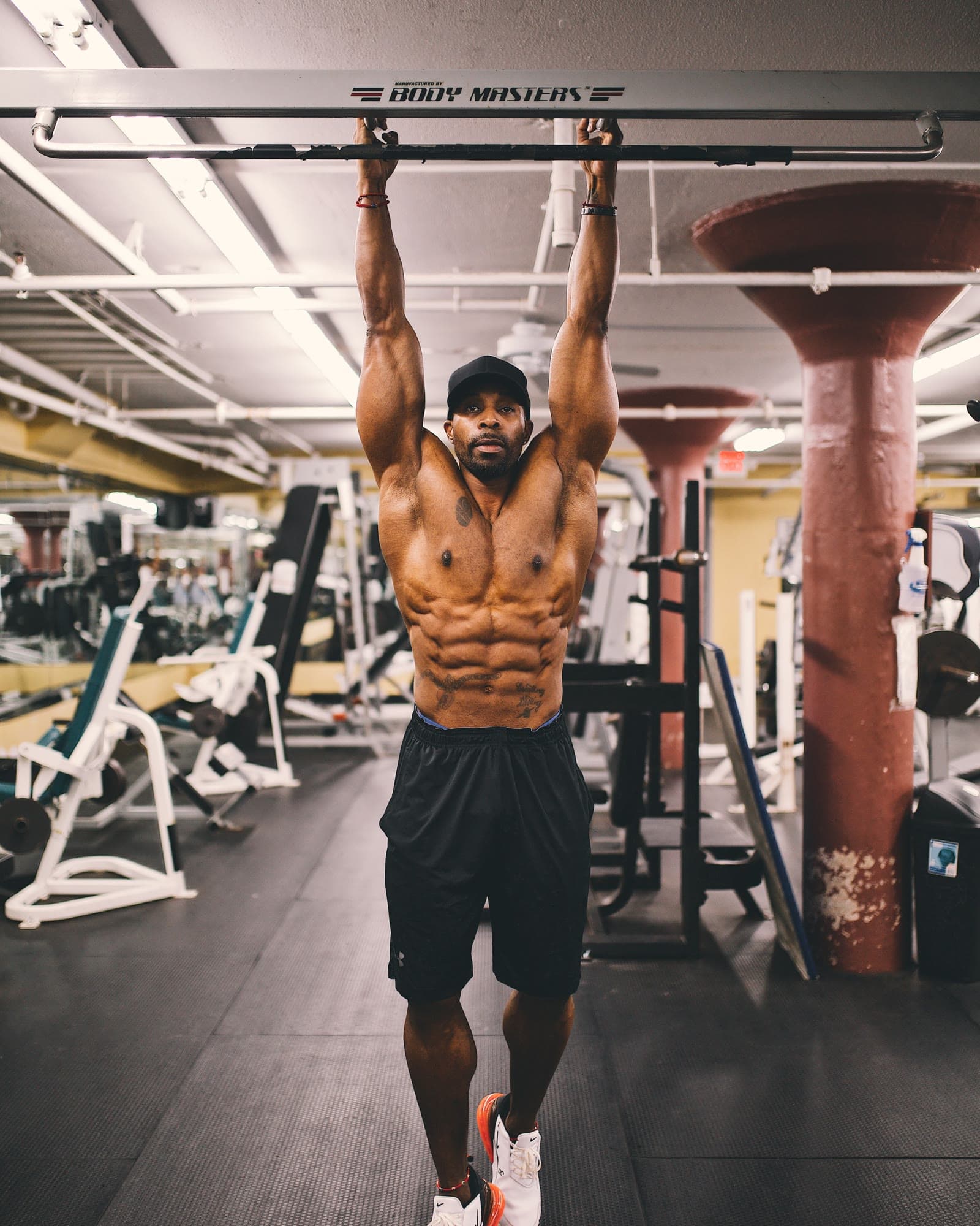Daine Chang, shirtless and lean, holding a hanging leg raise