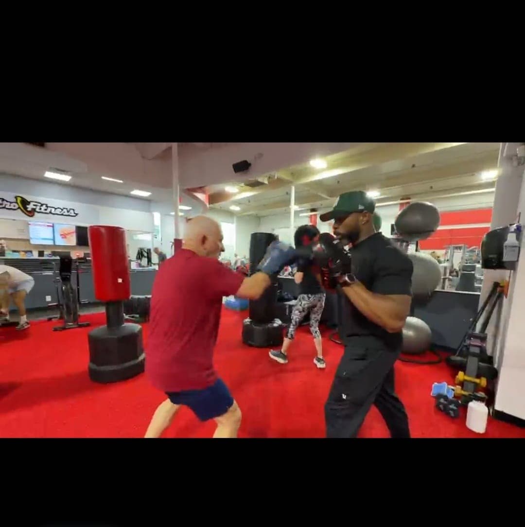 Daine Chang on the pads with an older client, seen across the gym